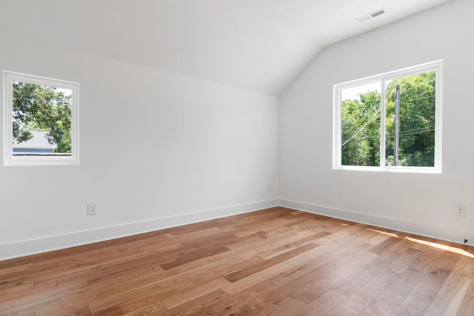 White sliding window in a bright, empty bedroom