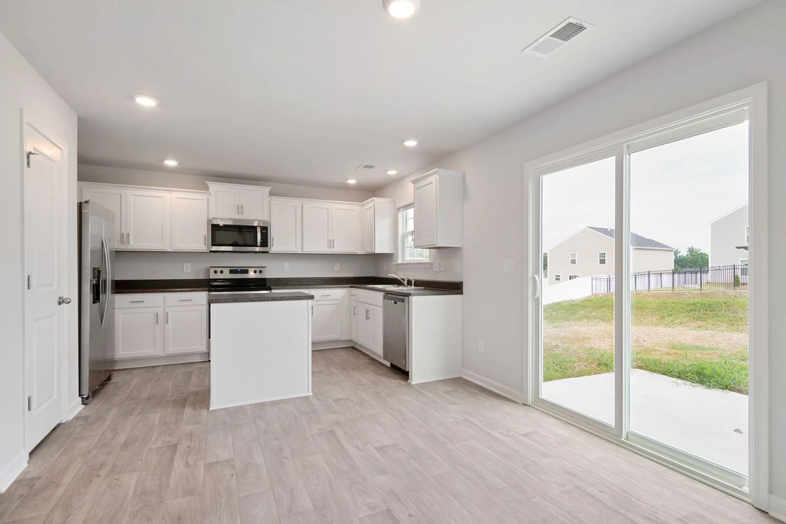 White sliding patio door in a kitchen opening to a backyard patio